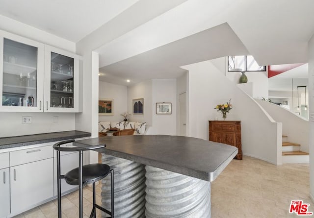 kitchen featuring kitchen peninsula, white cabinetry, and a breakfast bar area