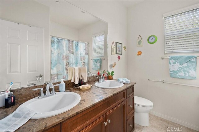 bathroom featuring tile patterned floors, a wealth of natural light, vanity, and toilet