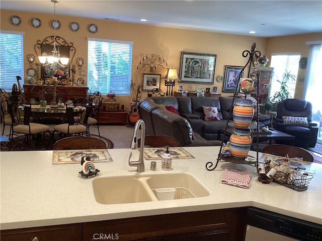 kitchen with dishwashing machine, dark brown cabinetry, hanging light fixtures, and sink