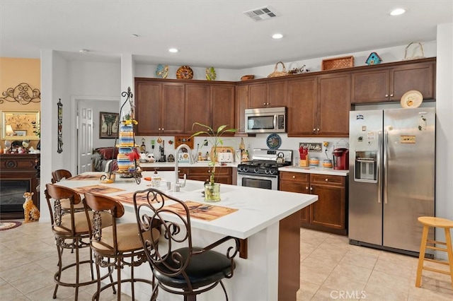 kitchen featuring a center island with sink, a kitchen breakfast bar, sink, light tile patterned floors, and stainless steel appliances