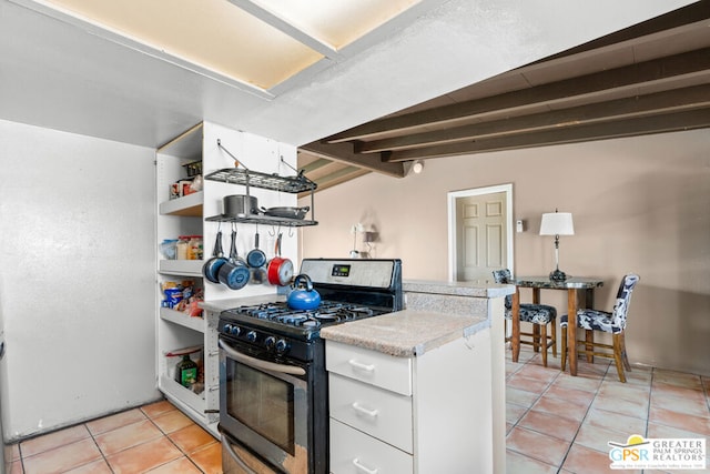 kitchen with white cabinetry, vaulted ceiling with beams, light tile patterned flooring, and gas range