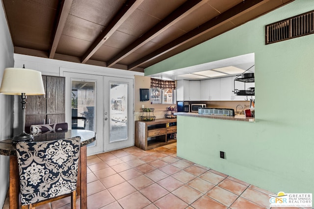 kitchen with french doors, lofted ceiling with beams, kitchen peninsula, white cabinets, and light tile patterned floors