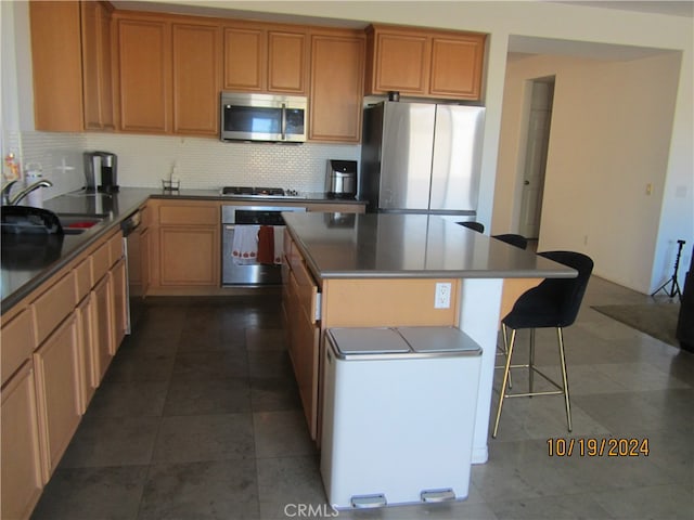 kitchen featuring appliances with stainless steel finishes, sink, backsplash, a center island, and dark tile patterned floors