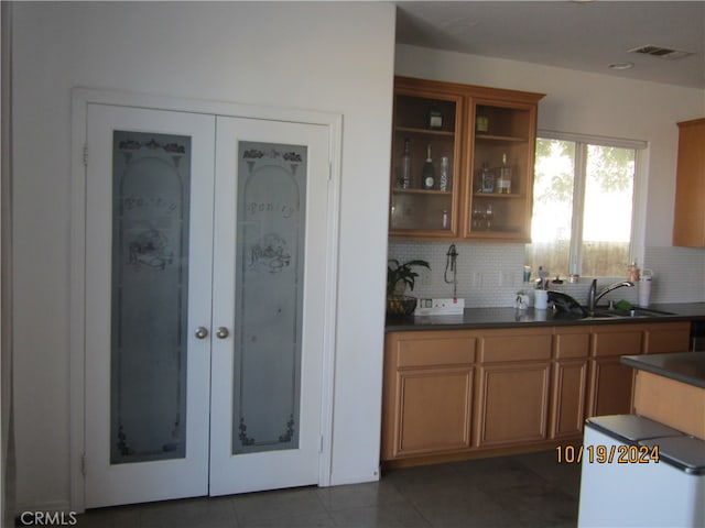 kitchen featuring sink, dark tile patterned flooring, and tasteful backsplash