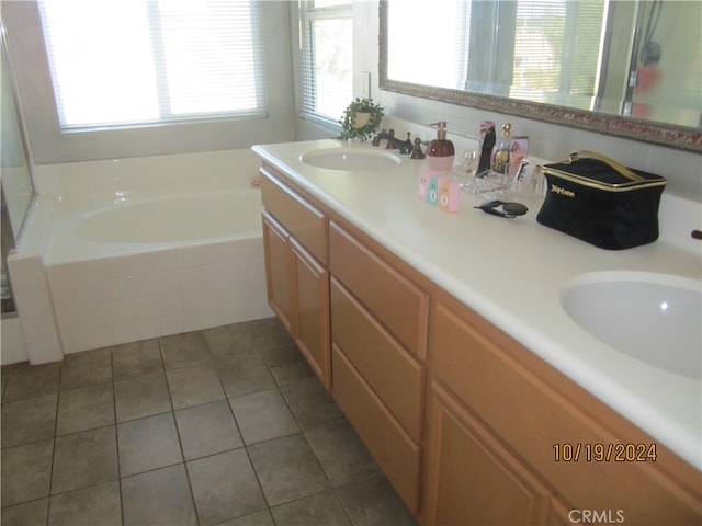 bathroom featuring vanity, a relaxing tiled tub, and plenty of natural light