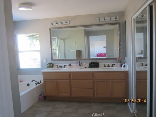 bathroom featuring vanity, a relaxing tiled tub, and tile patterned flooring