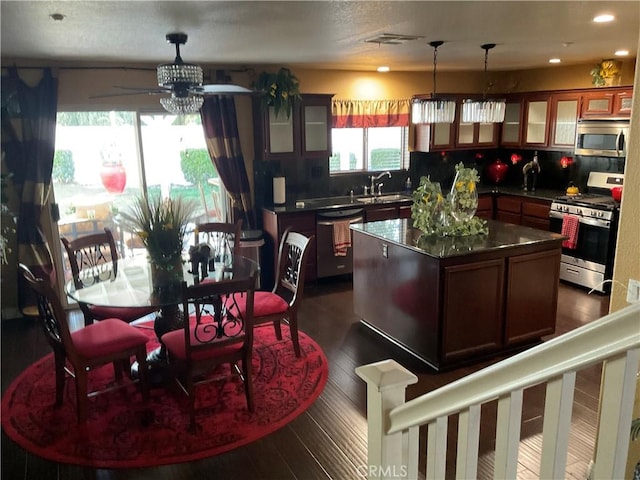 kitchen featuring appliances with stainless steel finishes, backsplash, sink, a kitchen island, and hanging light fixtures