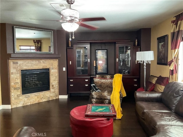 living room with dark hardwood / wood-style floors, ceiling fan, and a tiled fireplace