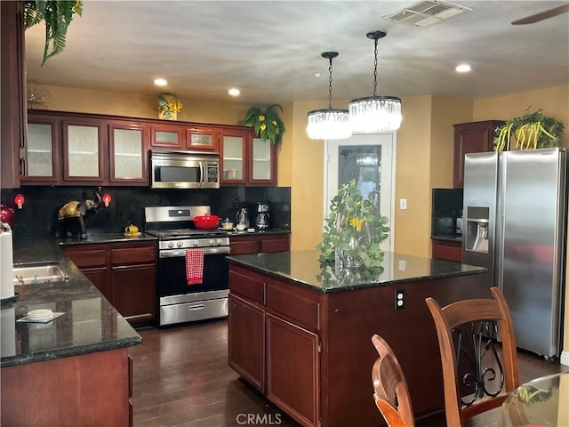 kitchen featuring a center island, dark hardwood / wood-style flooring, backsplash, pendant lighting, and appliances with stainless steel finishes