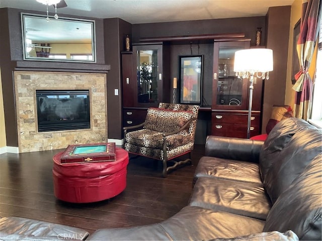 living room featuring a tiled fireplace and dark wood-type flooring