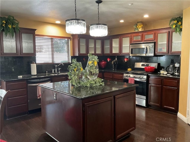 kitchen with appliances with stainless steel finishes, tasteful backsplash, a kitchen island, and dark hardwood / wood-style floors