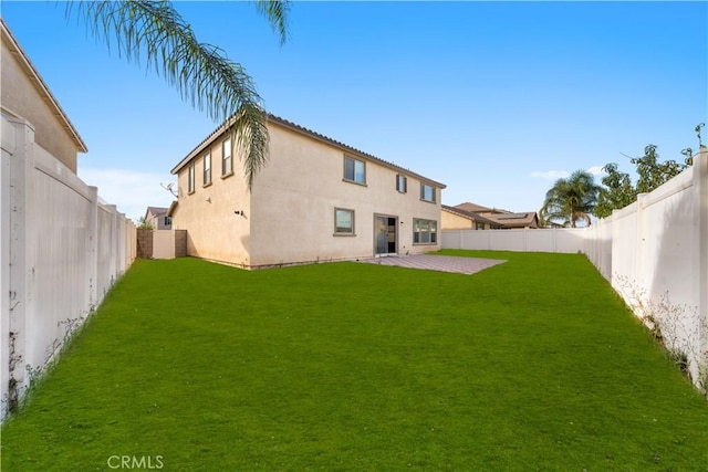 rear view of house featuring a lawn and a patio