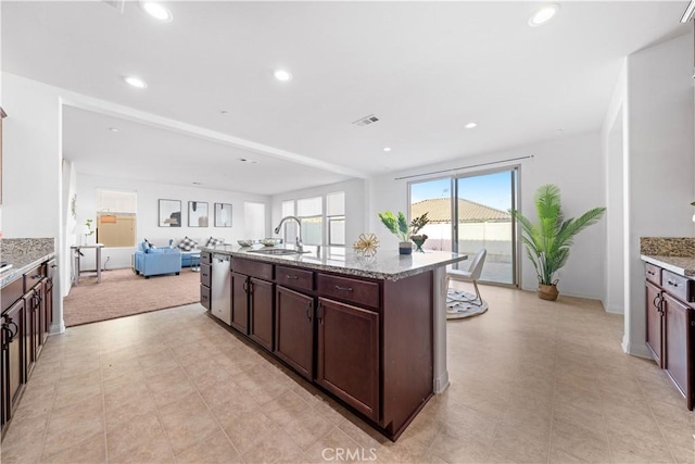 kitchen with a kitchen island with sink, sink, stainless steel dishwasher, light stone countertops, and dark brown cabinetry