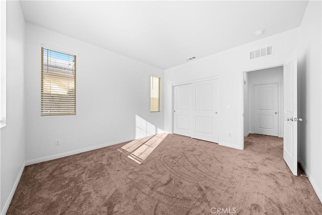 unfurnished bedroom with light carpet and a closet