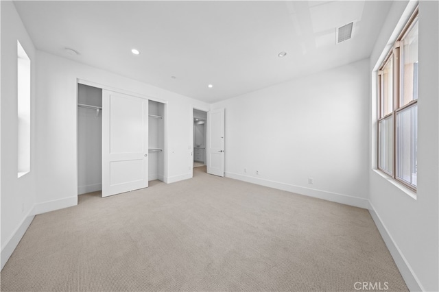 unfurnished bedroom with multiple windows, a closet, and light colored carpet