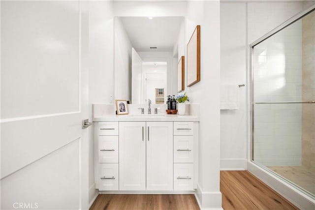 bathroom featuring hardwood / wood-style floors, vanity, and a shower with shower door