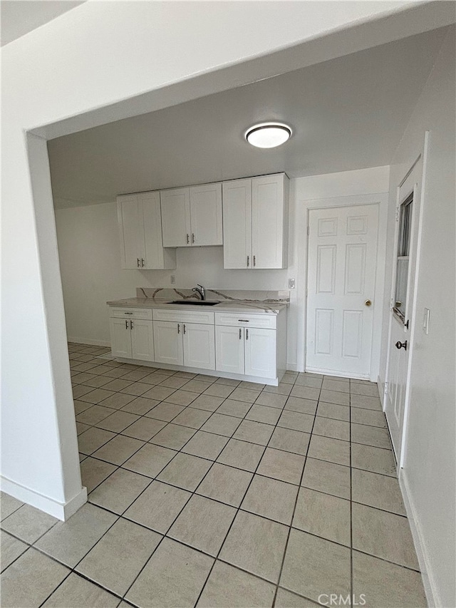 kitchen featuring light tile patterned floors, sink, and white cabinets