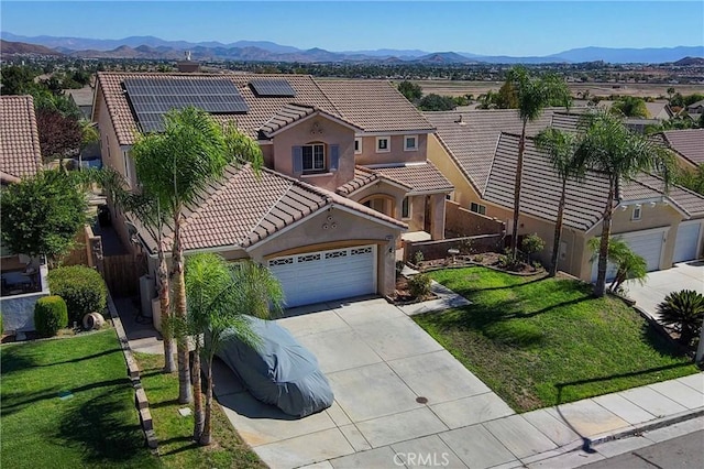 view of front facade with a mountain view, solar panels, and a front yard