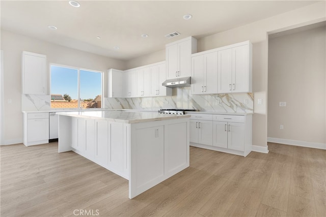 kitchen with decorative backsplash, light hardwood / wood-style flooring, white cabinets, and a kitchen island