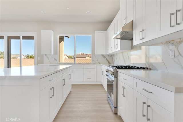 kitchen with light hardwood / wood-style floors, high end stainless steel range, white cabinets, and extractor fan