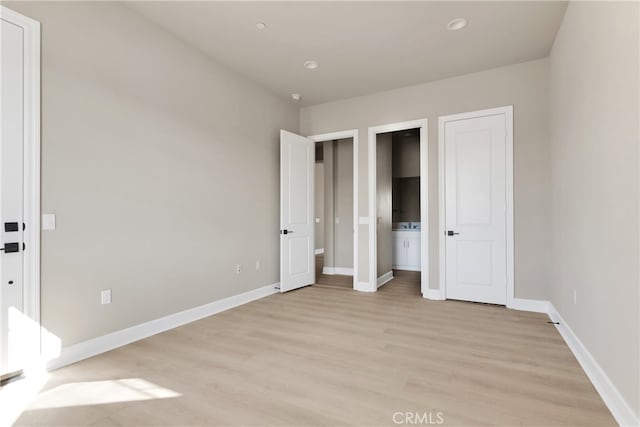 unfurnished bedroom featuring connected bathroom and light wood-type flooring