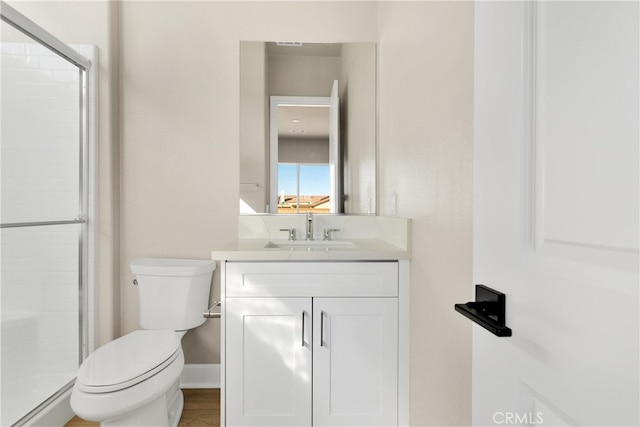 bathroom featuring vanity, toilet, and a shower with door