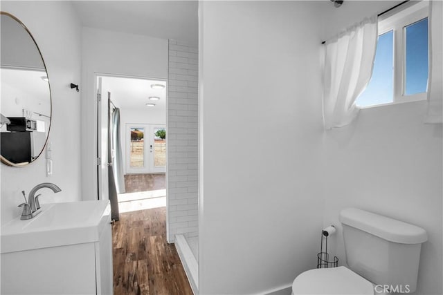 bathroom with french doors, walk in shower, vanity, hardwood / wood-style floors, and toilet