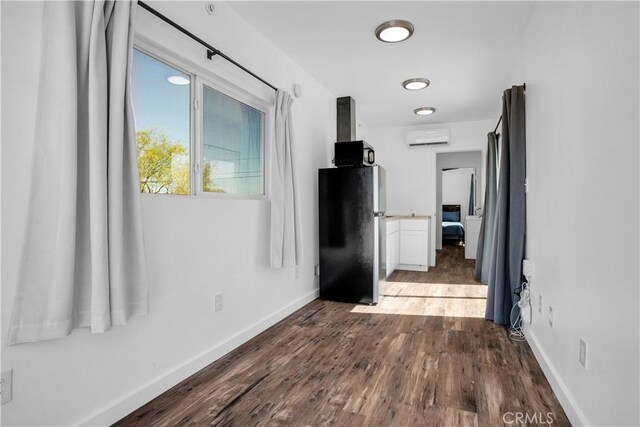 corridor with hardwood / wood-style floors and a wall unit AC