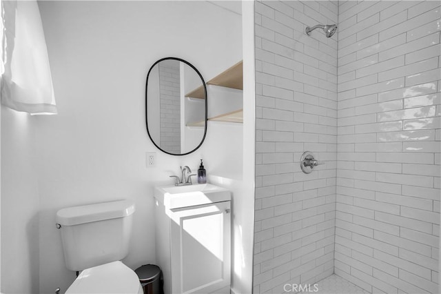 bathroom with a tile shower, vanity, and toilet