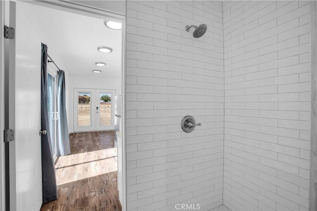 bathroom with wood-type flooring, a tile shower, and french doors