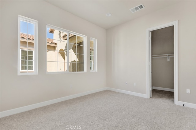 unfurnished bedroom featuring a walk in closet and light colored carpet