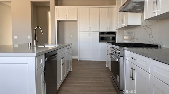 kitchen featuring a kitchen island with sink, sink, ventilation hood, white cabinets, and appliances with stainless steel finishes