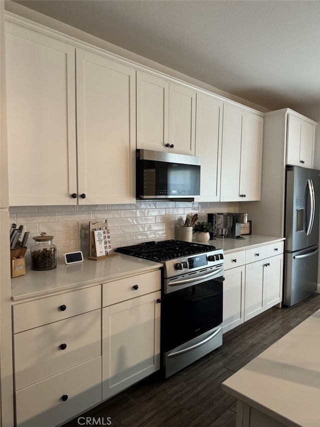 kitchen featuring white cabinetry, stainless steel appliances, dark hardwood / wood-style floors, and tasteful backsplash