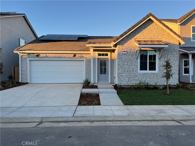 view of front of house with a garage, a front lawn, and solar panels