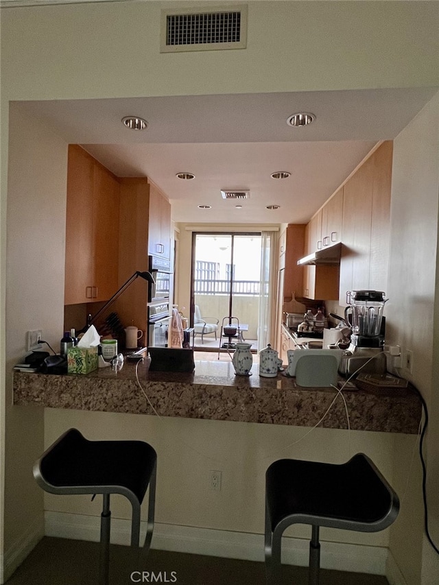 11847 Gorham Ave Unit 403, Los Angeles, CA 90049 - kitchen featuring under cabinet range hood, a peninsula, and visible vents