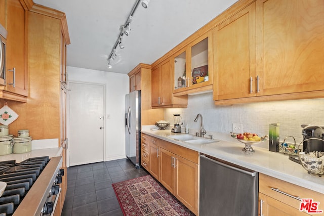 kitchen featuring backsplash, track lighting, stainless steel appliances, sink, and dark tile patterned flooring