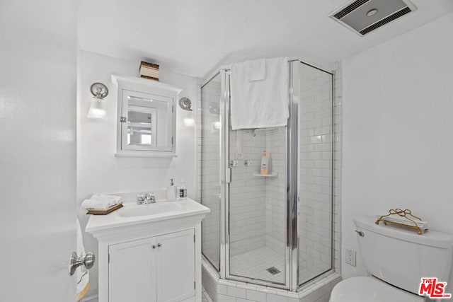 bathroom featuring vanity, a shower with shower door, and toilet