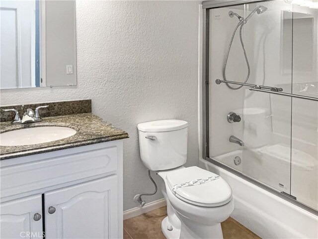 full bathroom with tile patterned floors, vanity, toilet, and bath / shower combo with glass door