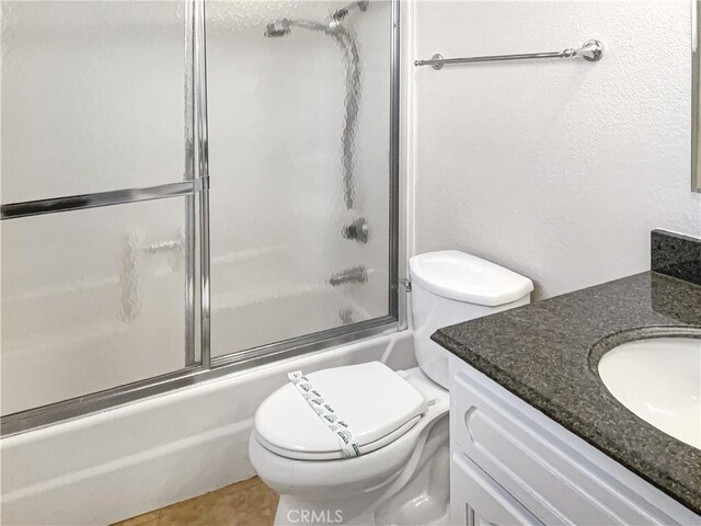 full bathroom featuring tile patterned floors, vanity, toilet, and enclosed tub / shower combo