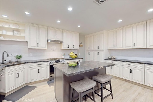 kitchen featuring stainless steel range, a center island, light hardwood / wood-style floors, and sink