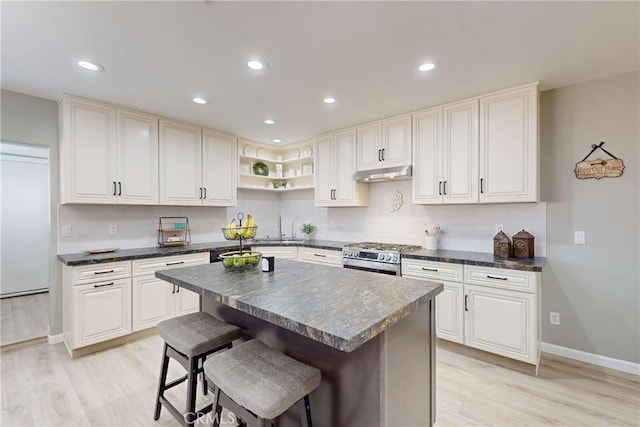 kitchen with sink, a center island, high end stainless steel range oven, and light wood-type flooring