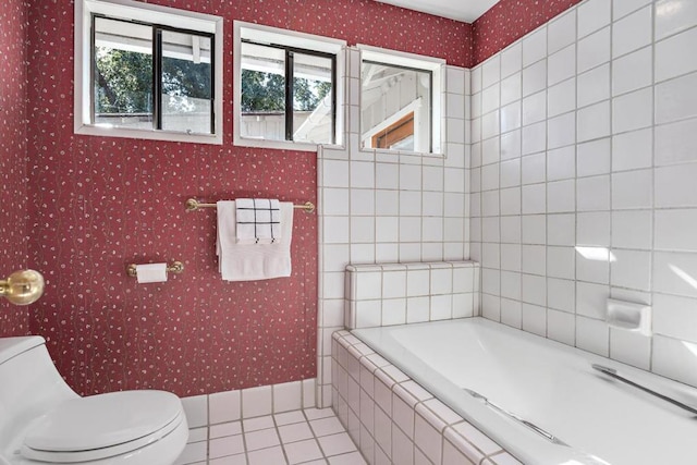 bathroom featuring toilet, tile patterned floors, and tiled bath