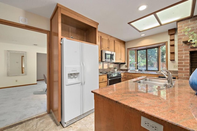 kitchen with white refrigerator with ice dispenser, light colored carpet, gas stove, light stone counters, and sink