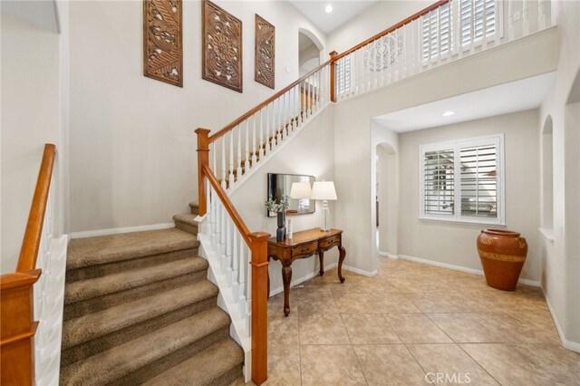 staircase featuring tile patterned flooring and a towering ceiling