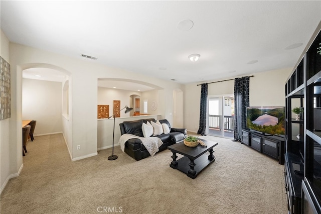 carpeted living area featuring visible vents, arched walkways, and baseboards