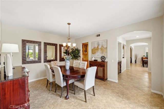 dining space with baseboards, visible vents, arched walkways, and a notable chandelier