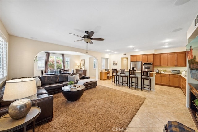 living room with arched walkways, a toaster, ceiling fan, and light tile patterned floors