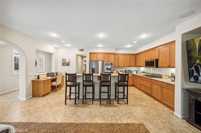 kitchen featuring visible vents, arched walkways, appliances with stainless steel finishes, a breakfast bar area, and light countertops