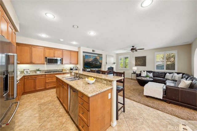 kitchen featuring an island with sink, ceiling fan, stainless steel appliances, a breakfast bar, and sink