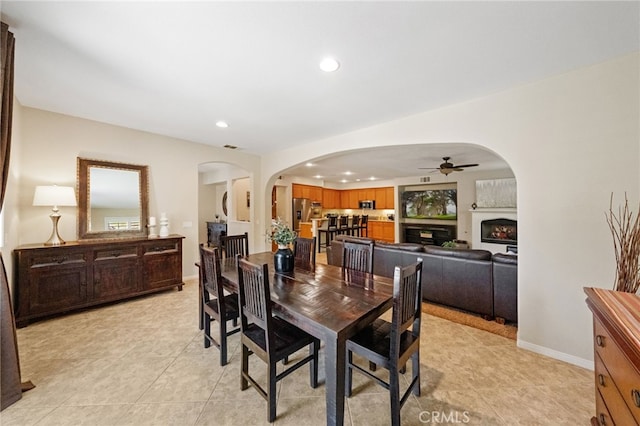 dining area with arched walkways, light tile patterned floors, a fireplace, and recessed lighting